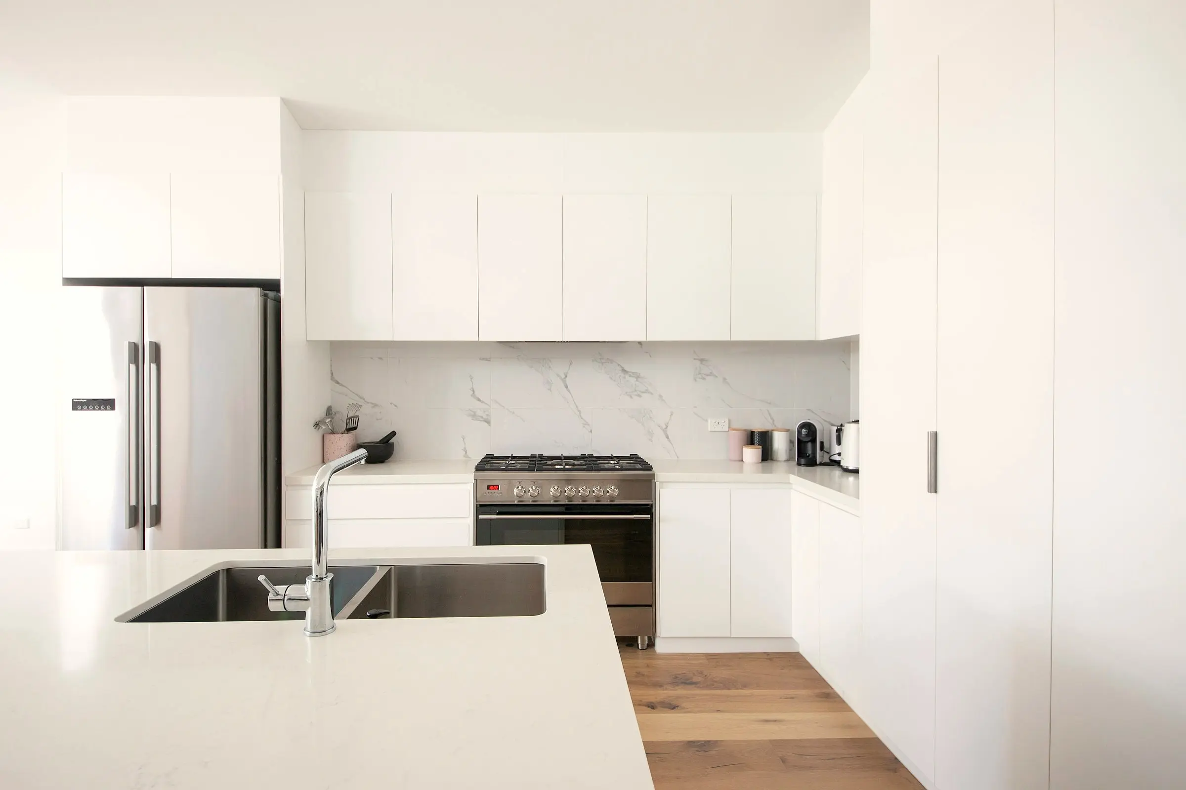 Cocina blanca de líneas rectas integrada en la zona de día