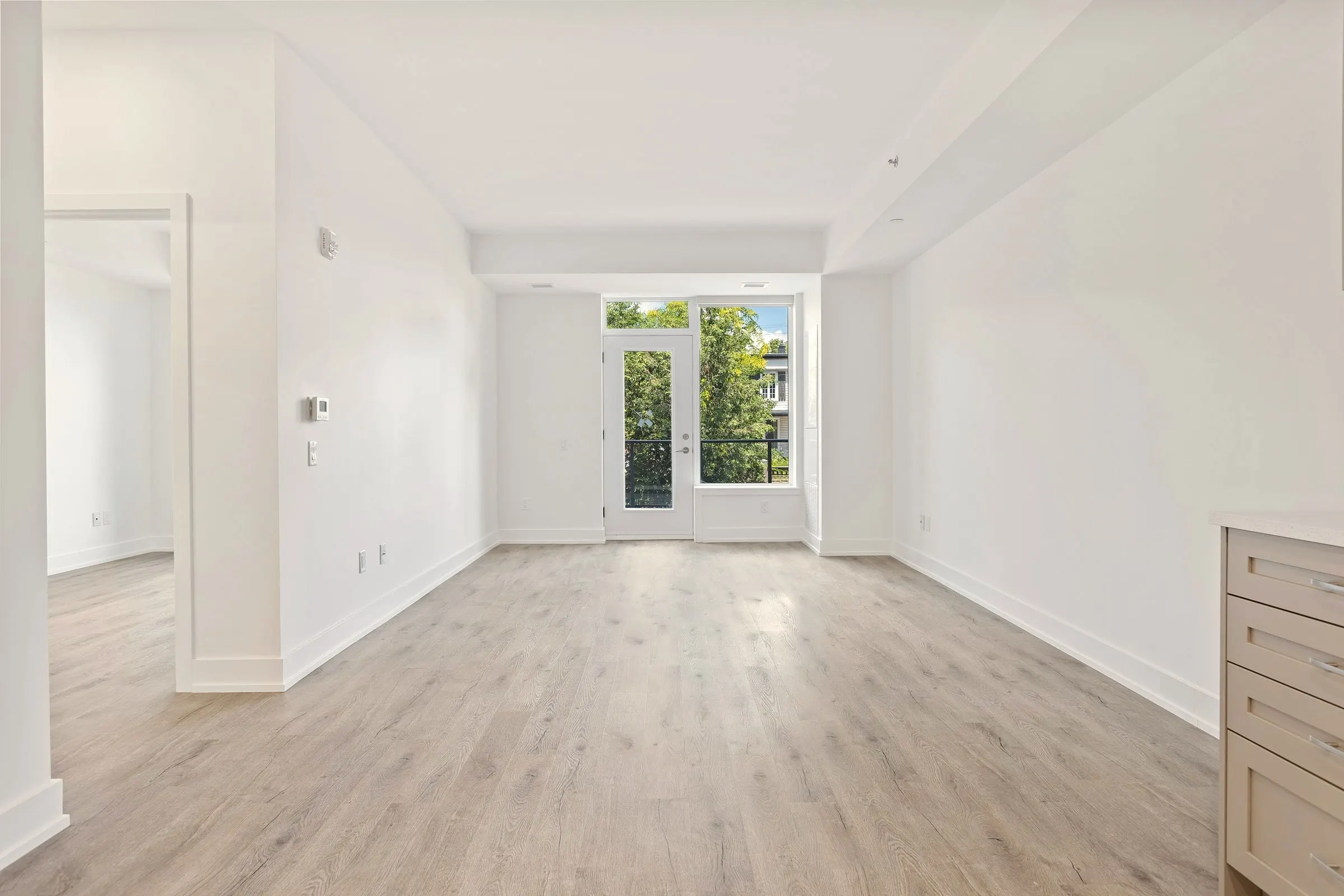 Estancia de una vivienda recién reformada, con parquet nuevo y luz natural entrando por el balcón